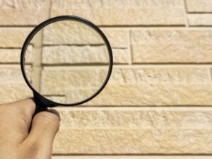 外壁を虫眼鏡で点検調査