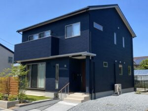 青空を背景にしたモダンな印象のネイビー外壁住宅